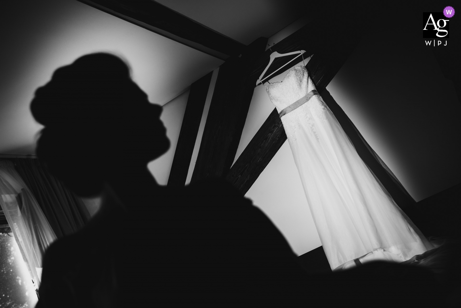 The bride's dress hung on the wall, illuminated by a soft light that highlighted the beautiful silhouetted profile of the bride