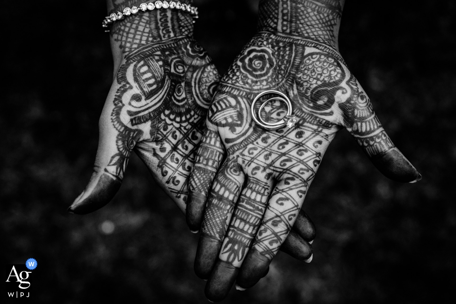 At Haute Garonne in Labarthe sur Lèze, a bride's hands holding her wedding rings, adorned with henna, were captured in a beautiful black and white image