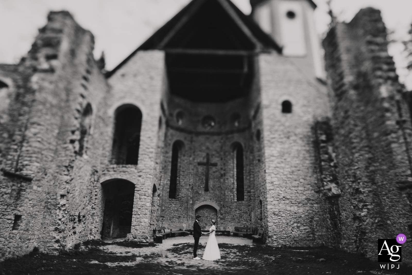 Ein malerisches Hochzeitsfoto zeigt ein schwarz-weißes Tilt-Shift-Porträt eines Brautpaares, das auf Schloss Hofgut Hohenkarpfen steht