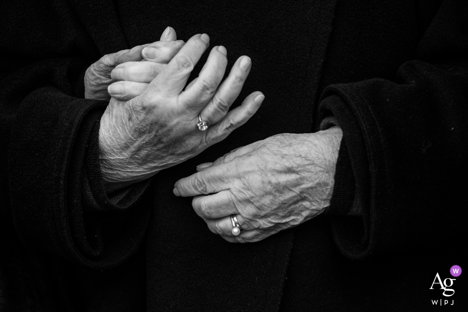 A black and white wedding photo of an elderly couple with their hands intertwined was taken at Hoeve De Blauwpoorte, with a heightened contrast for a more detailed shot