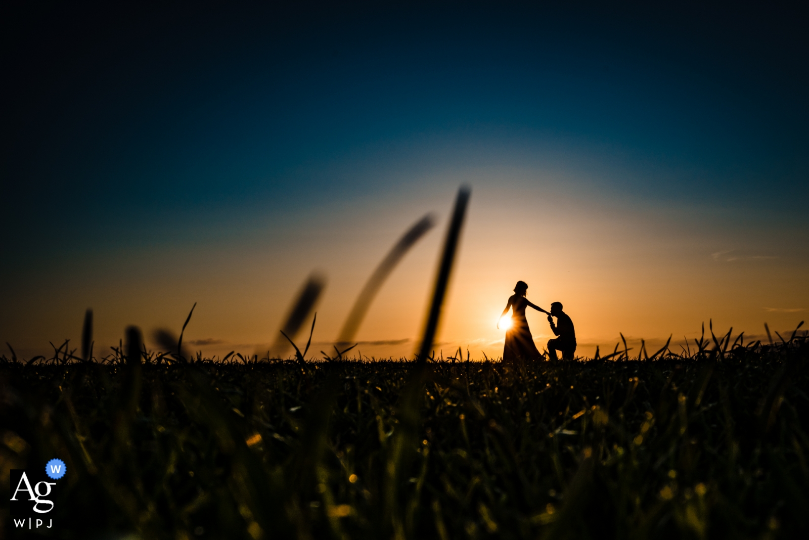 Ein romantisches Sonnenuntergangsporträt als Silhouette, das zeigt, wie der Bräutigam die Hand seiner Braut küsst, wurde bei einer Hochzeit in Garden Grove, Kalifornien, aufgenommen