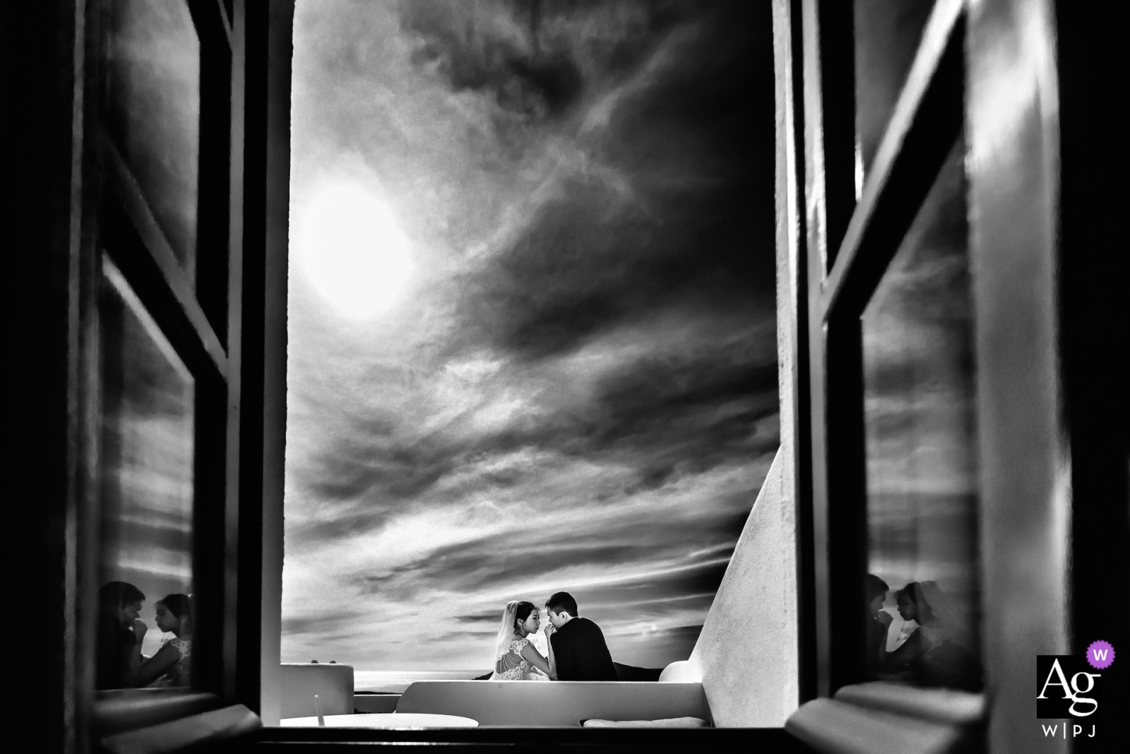 Une photo d'un couple assis à l'extérieur en noir et blanc serein a pris vie dans les horizons infinis de Santorin, en Grèce, le jour du mariage