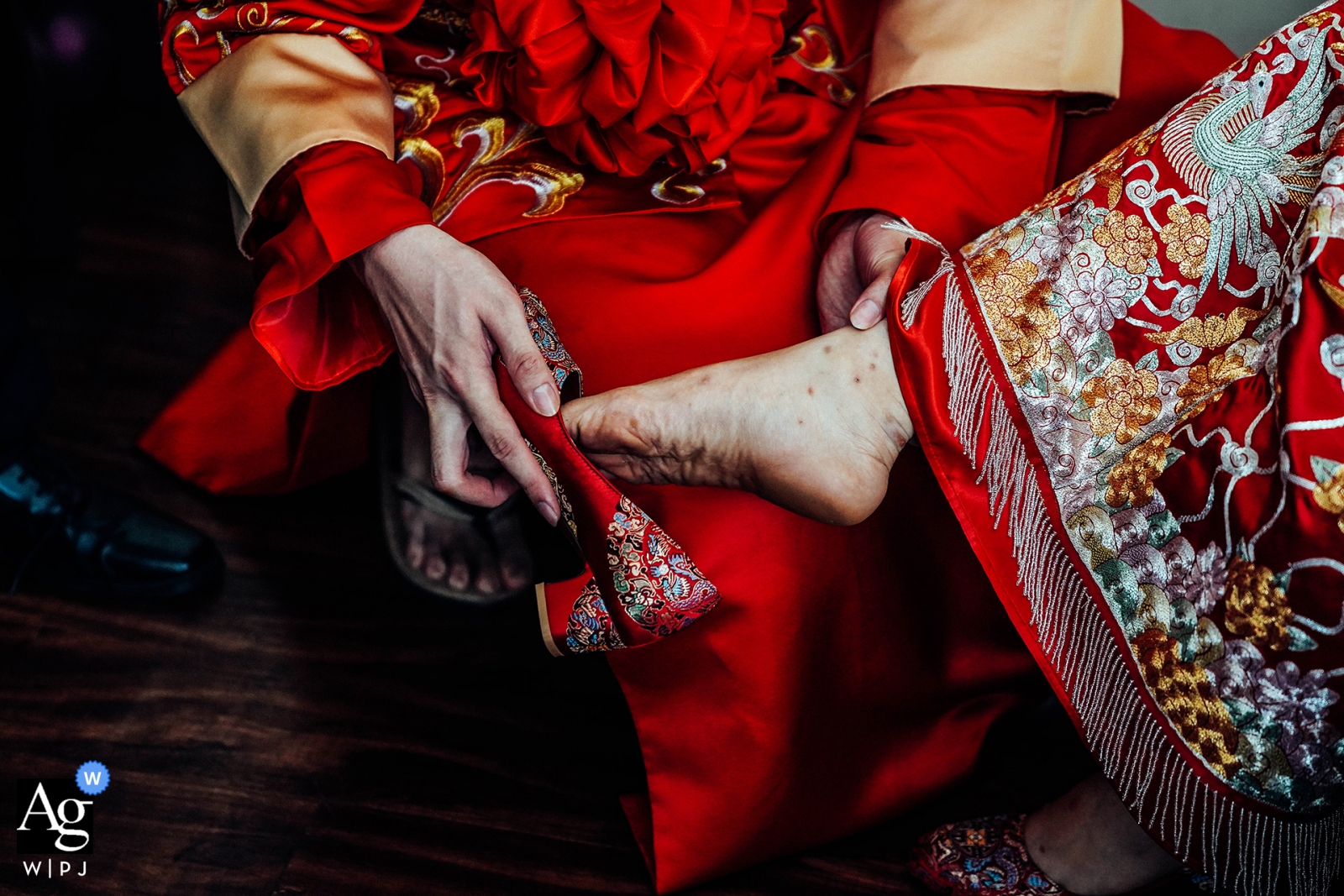 A wedding picture of a woman having a red heel shoe put on her by a man was taken at Hoi An