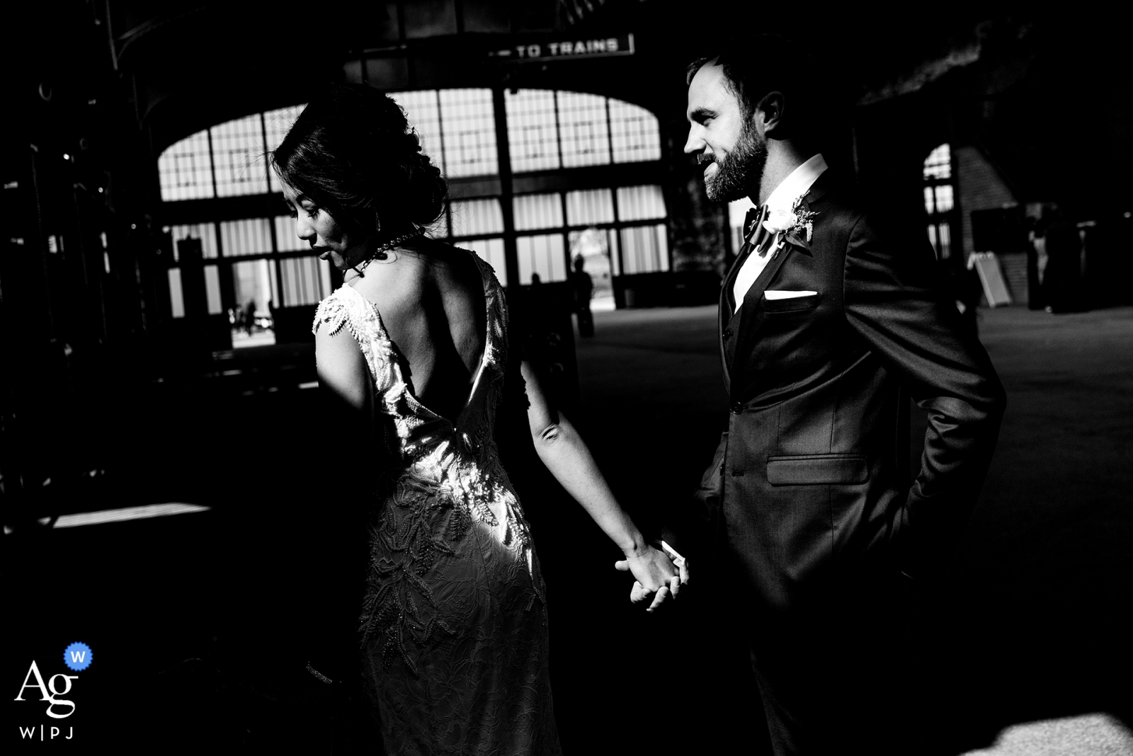 The couple were holding hands at Maritime Parc, NJ, in a wedding photo capturing the industrial architecture of the train station