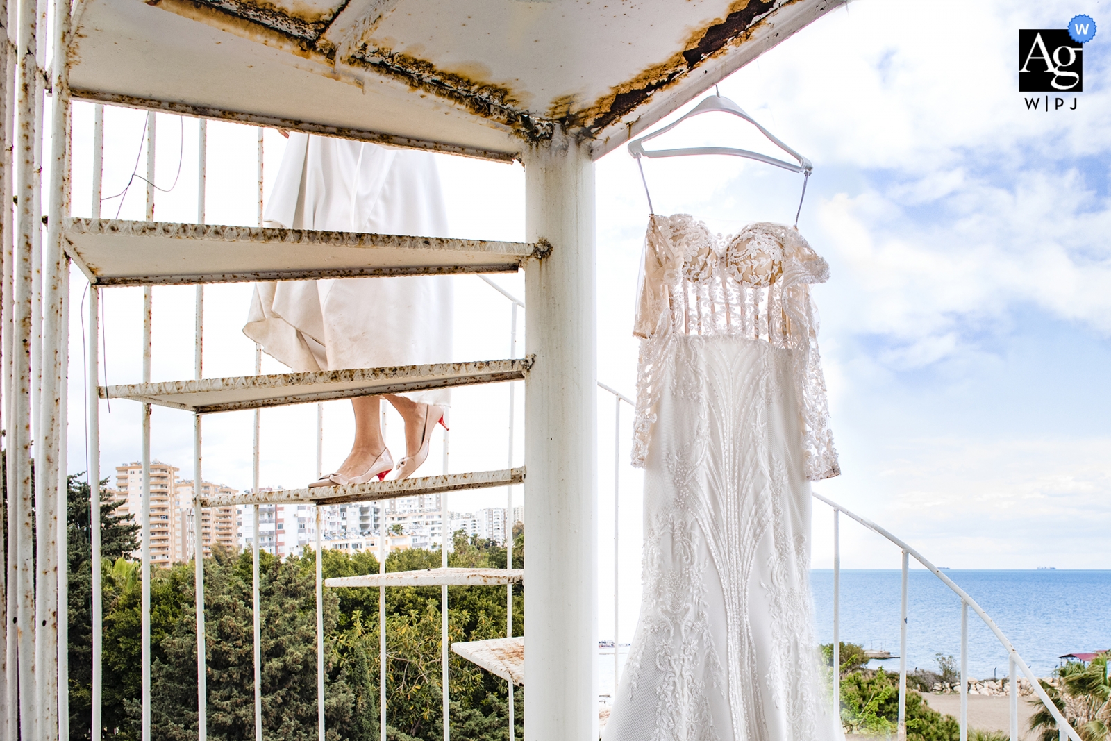 En Mersin, Turquía, la vista exterior del océano de la novia queda inmortalizada al descender las escaleras de caracol cerca de su vestido de novia colgado.