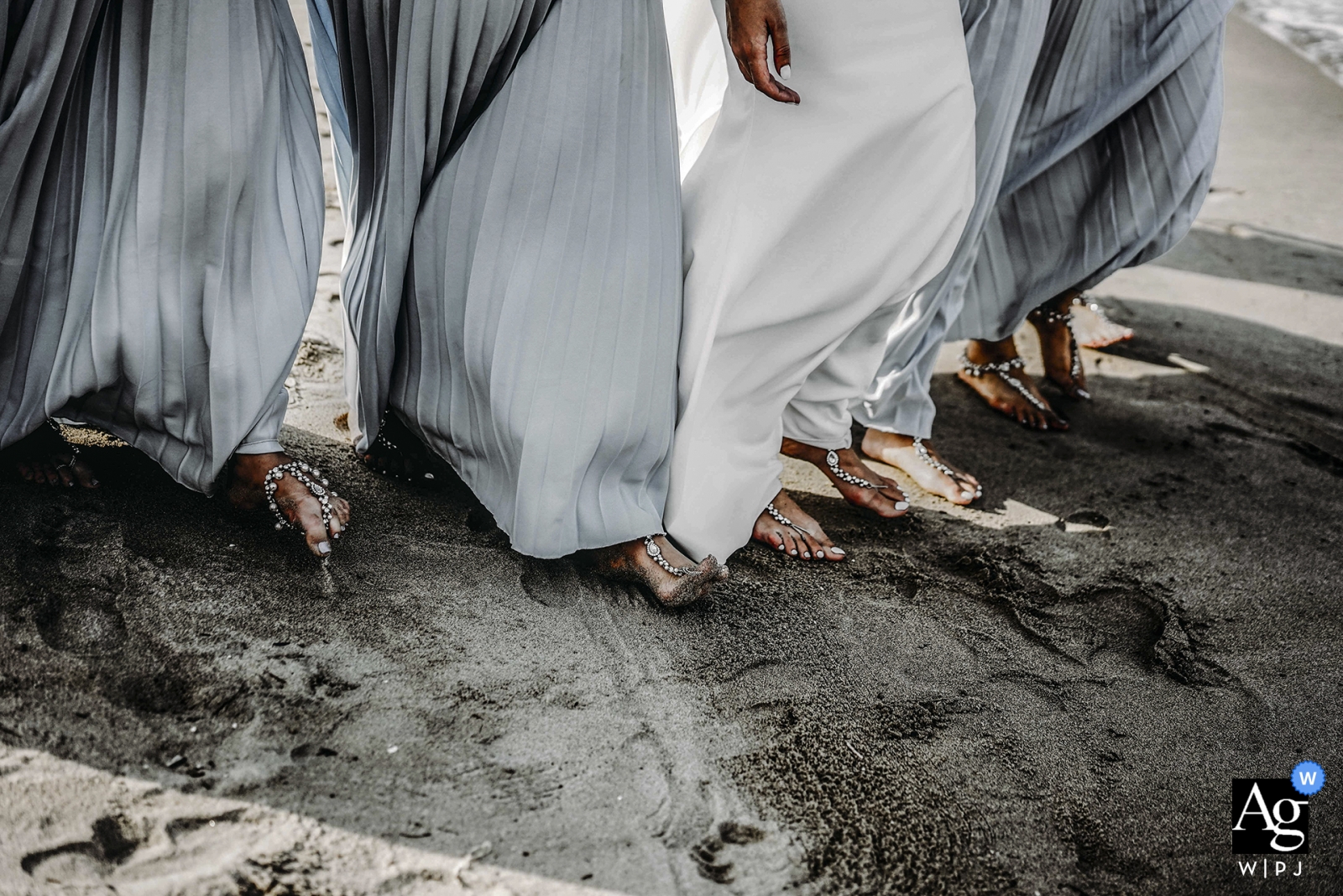 Questa fotografia di matrimonio, scattata nella città di Hoi An, mostra gli orli degli abiti della sposa e degli accompagnatori che si muovono leggermente nella brezza dell'oceano