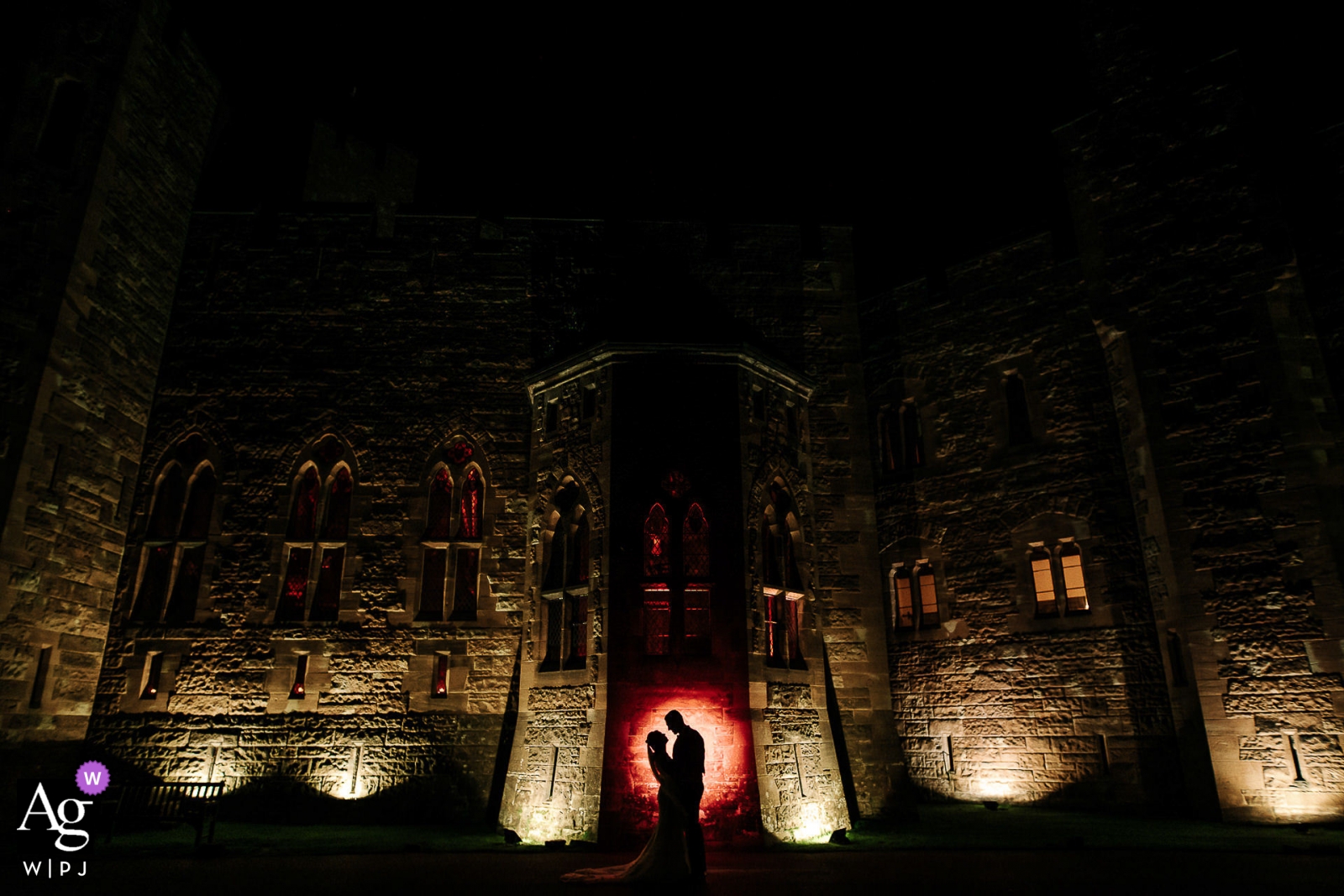 Foto door: <a href="https://www.wpja.com/photos/artistic-wedding-photographers/2469281"> Andy Griffiths - St. Helens Lancashire De bruiloftsfotograaffotograaf van Engeland ontwierp dit portret van de bruid en bruidegom die 's nachts voor het Peckforton Castle staan