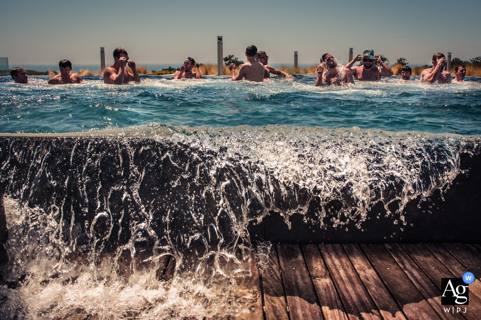 Uma foto de casamento tirada nas Areias do Seixo, em Portugal, mostra a alegre celebração do dia especial, capturada com água da piscina externa em cascata até a borda