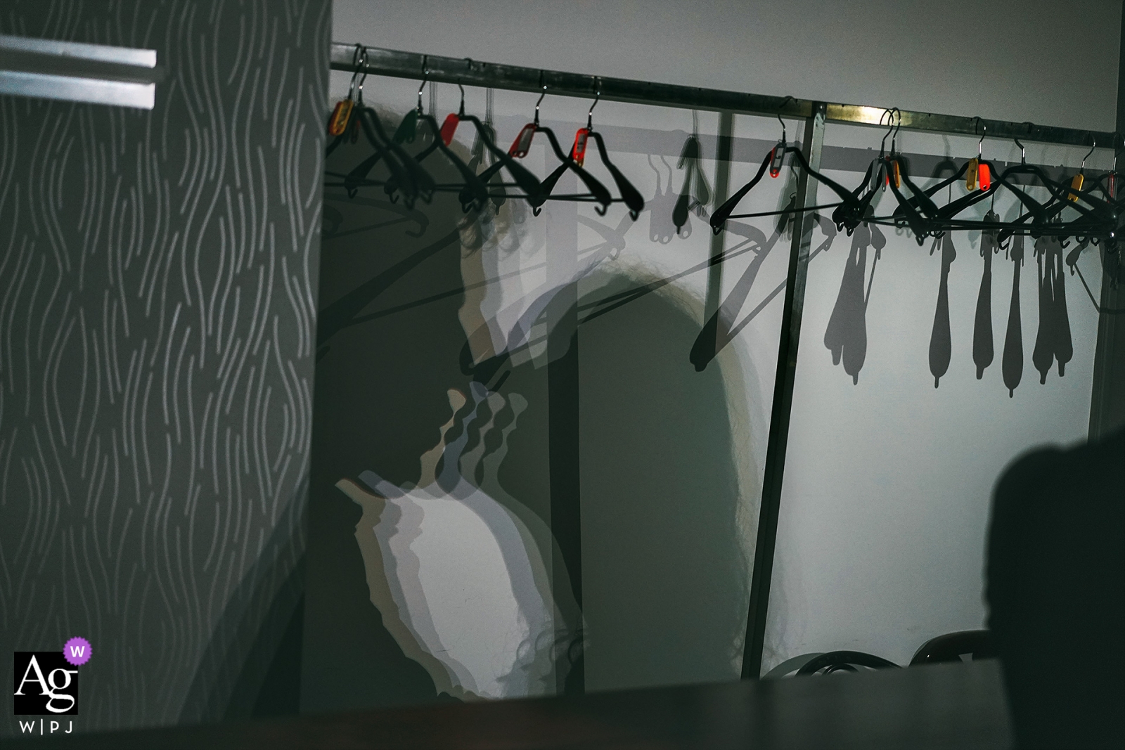 A romantic wedding photo was captured at Puerta De Jeronimos, showing the bride and groom shadows cast on the closet wall full of clothes hangers