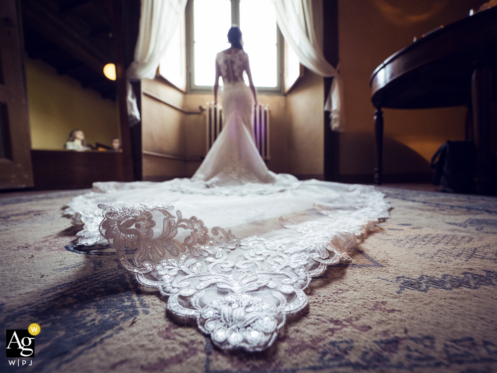 Una fotografía de boda tomada en Villa Semenza en Santa Maria Hoè, Italia, captura el momento en que la novia se está preparando, con su vestido extendido en el suelo y un encuadre simétrico con un estilo cinematográfico de bellas artes.