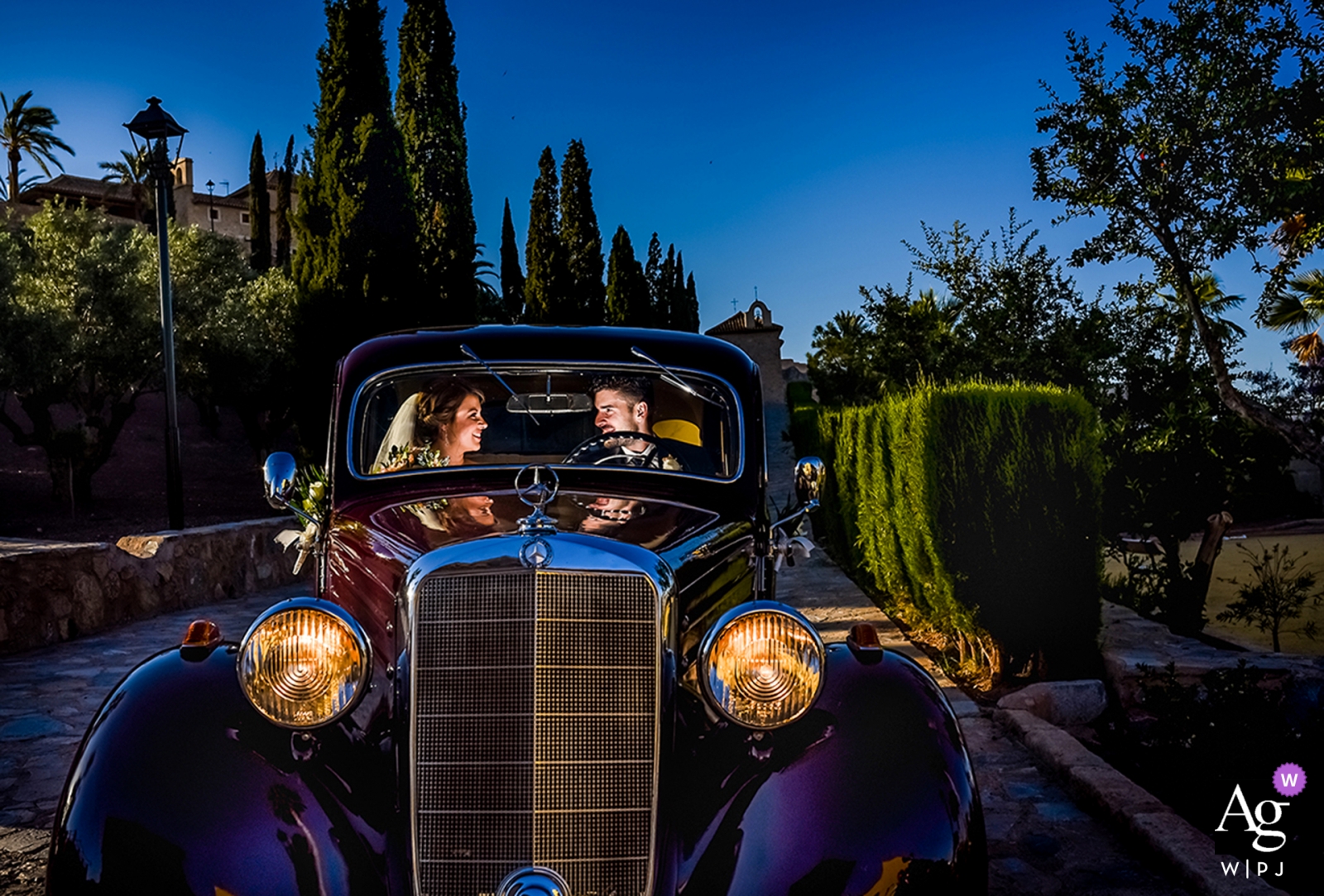 Una foto de boda antigua de una pareja de recién casados ​​dentro de un automóvil, iluminada desde adentro, fue tomada después de su ceremonia en Lorca, España.