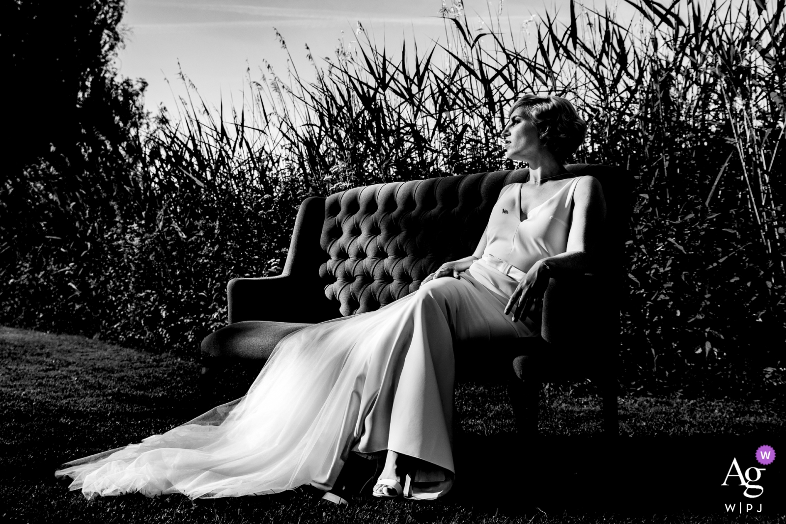 A bride is pictured sitting on a comfortable couch outdoors in the sun on her wedding day at Töpferhaus Alt Duvenstedt