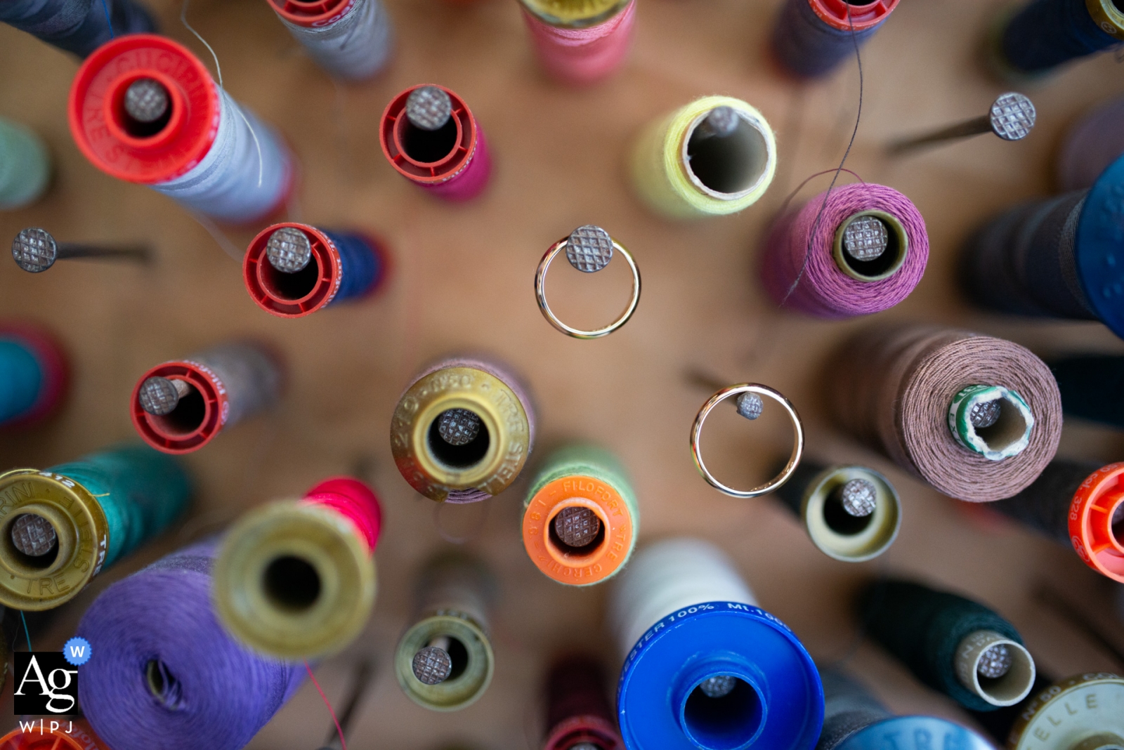 This wedding picture captures a close-up of the rings and sewing bobbins before a wedding at Chiesa di Iolo and Villa Il Petriccio.