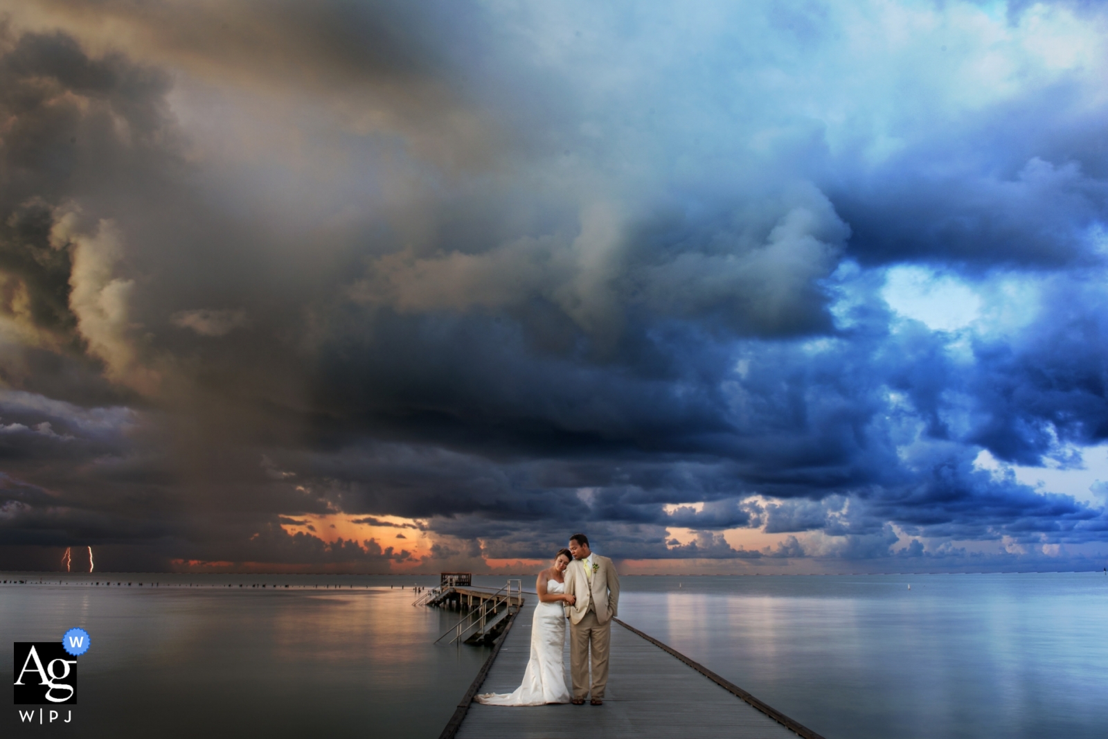 A picture of newlyweds taken at sunrise in Key West displaying a beautiful backdrop of a lightning strike in the distant sky