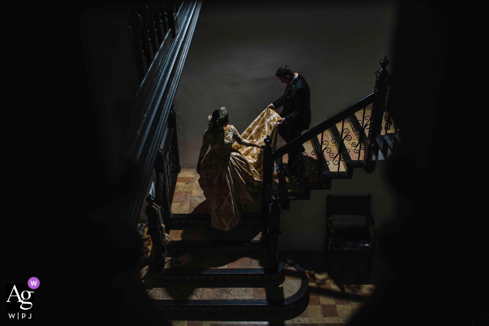 Une photo d'un mariage à Chiva montre le couple descendant les escaliers avec le marié aidant avec sa robe dans un bon éclairage