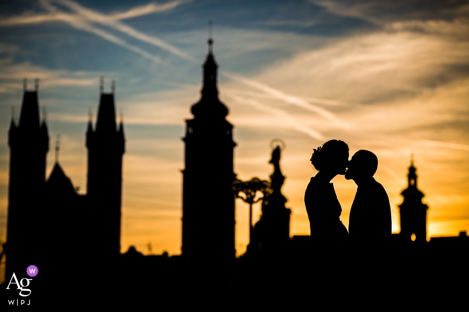 A wedding couple in silhouette embracing against the evening skyline of Nové Adalbertinum can be seen in this romantic wedding photo