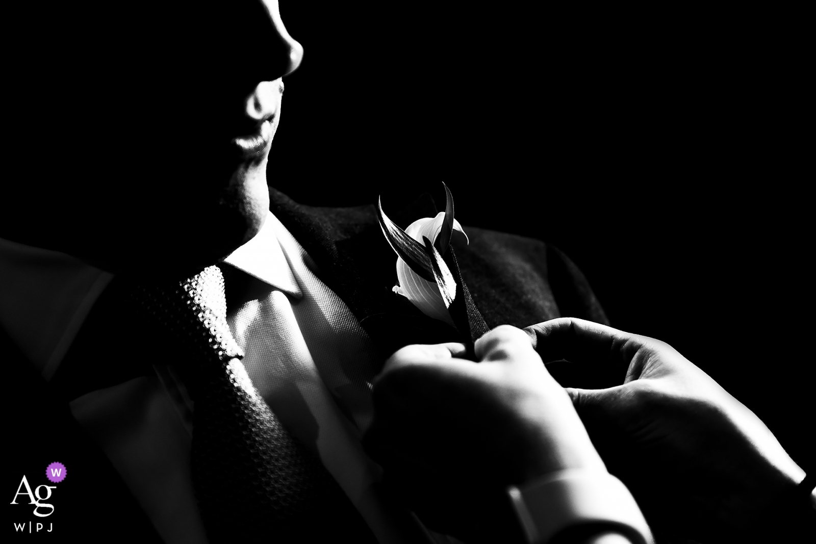 Foto von: <a href="https://www.wpja.com/photos/artistic-wedding-photographers/2513396"> Jesse La Plante - Boulder Colorado Schwarzweiss-Foto des Bräutigams, der seinen Boutonniere an feststecken lässt.