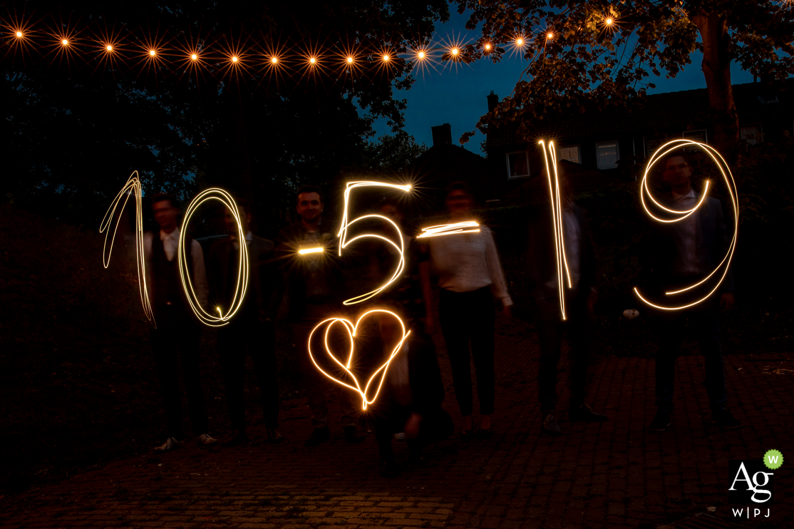 Fotografia de local de casamento de Puur Achter De Markt | Amigos do noivo estão escrevendo a data do casamento com luz.