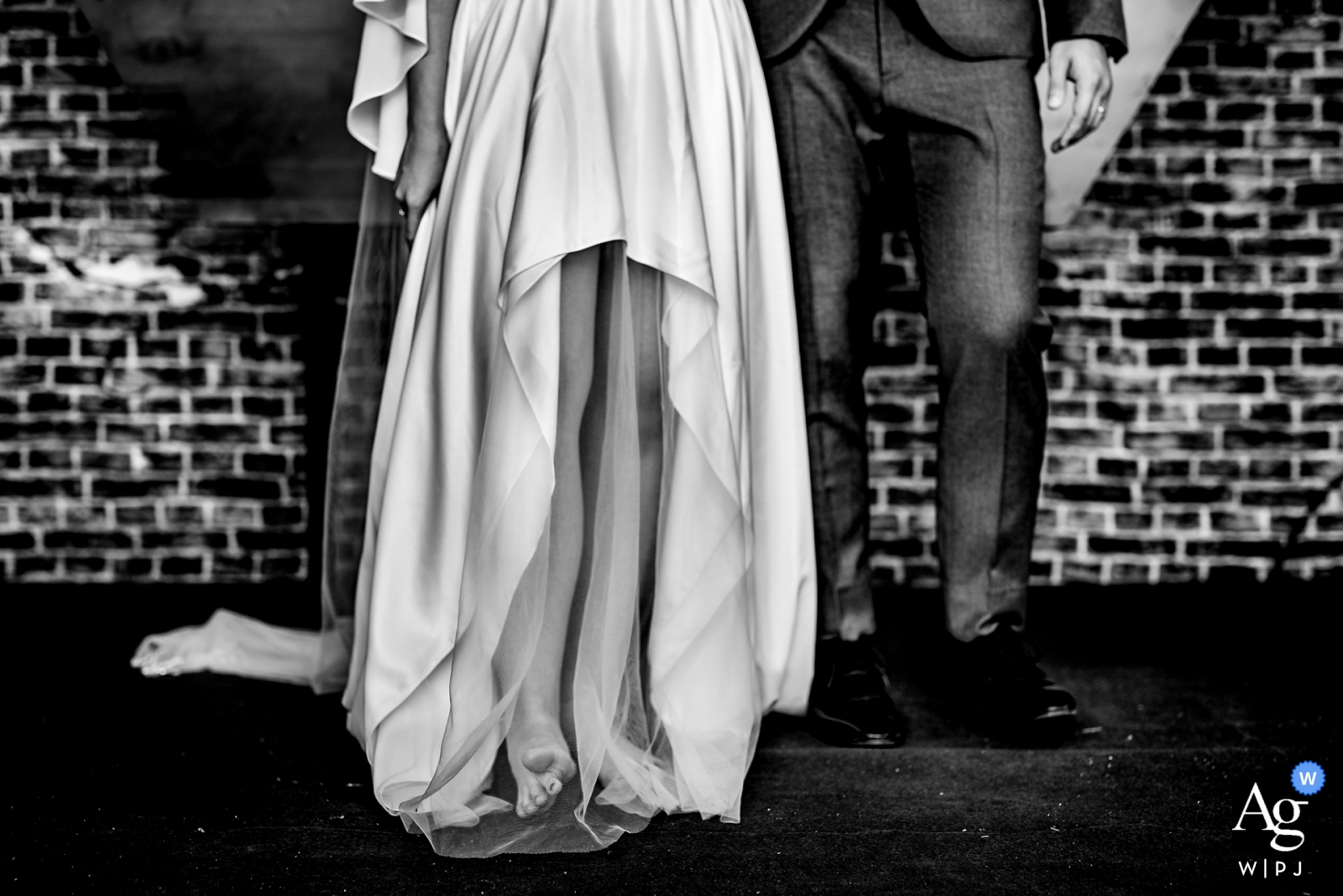 The bride and groom's legs were photographed against the rustic brick wall at their Phu Quoc wedding