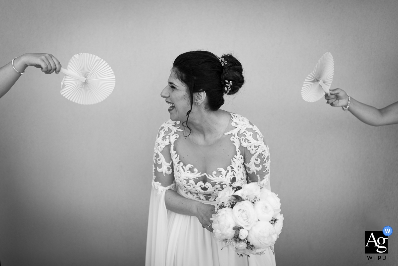 La hermosa novia, estaba radiante con su vestido blanco, sosteniendo un ramo de flores mientras sus ayudantes la abanicaban en su día especial.