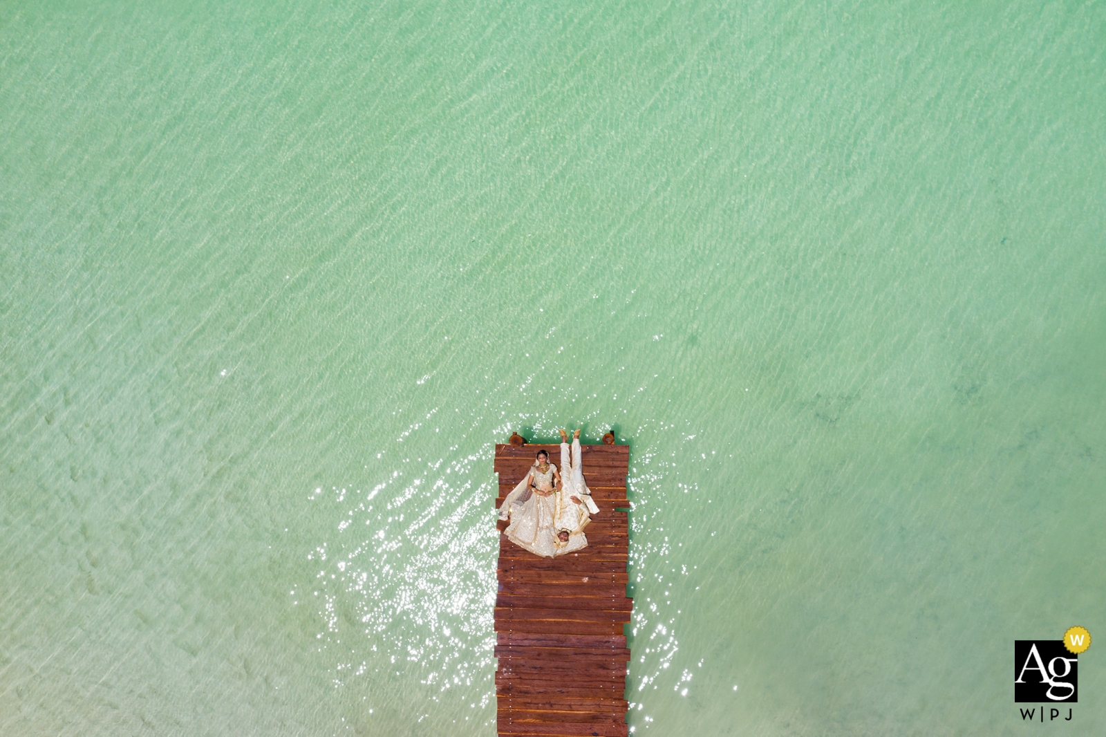 A bela noiva e o noivo deitam-se no cais em Cancun, México, de uma câmera drone