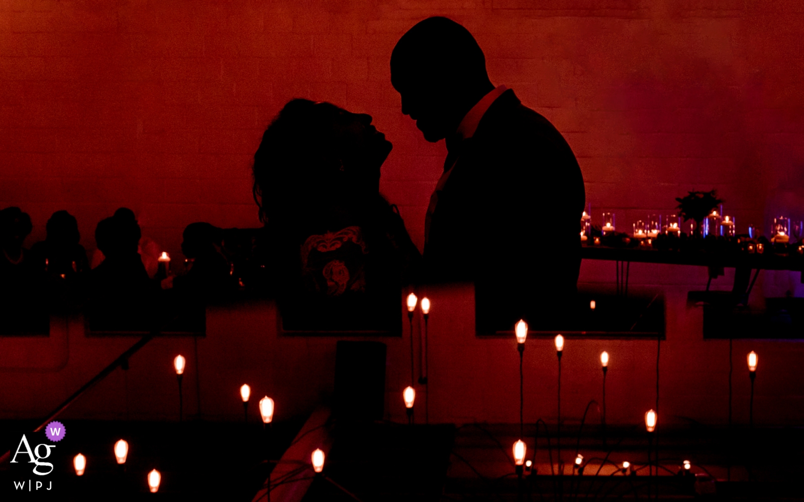 The newlyweds, a bride and groom, stood in silhouette against the backdrop of the Atlanta city skyline at nightfall, their contours illuminated by the contrast of the red inner city lights and the darkness of the night at the Upstairs Atlanta