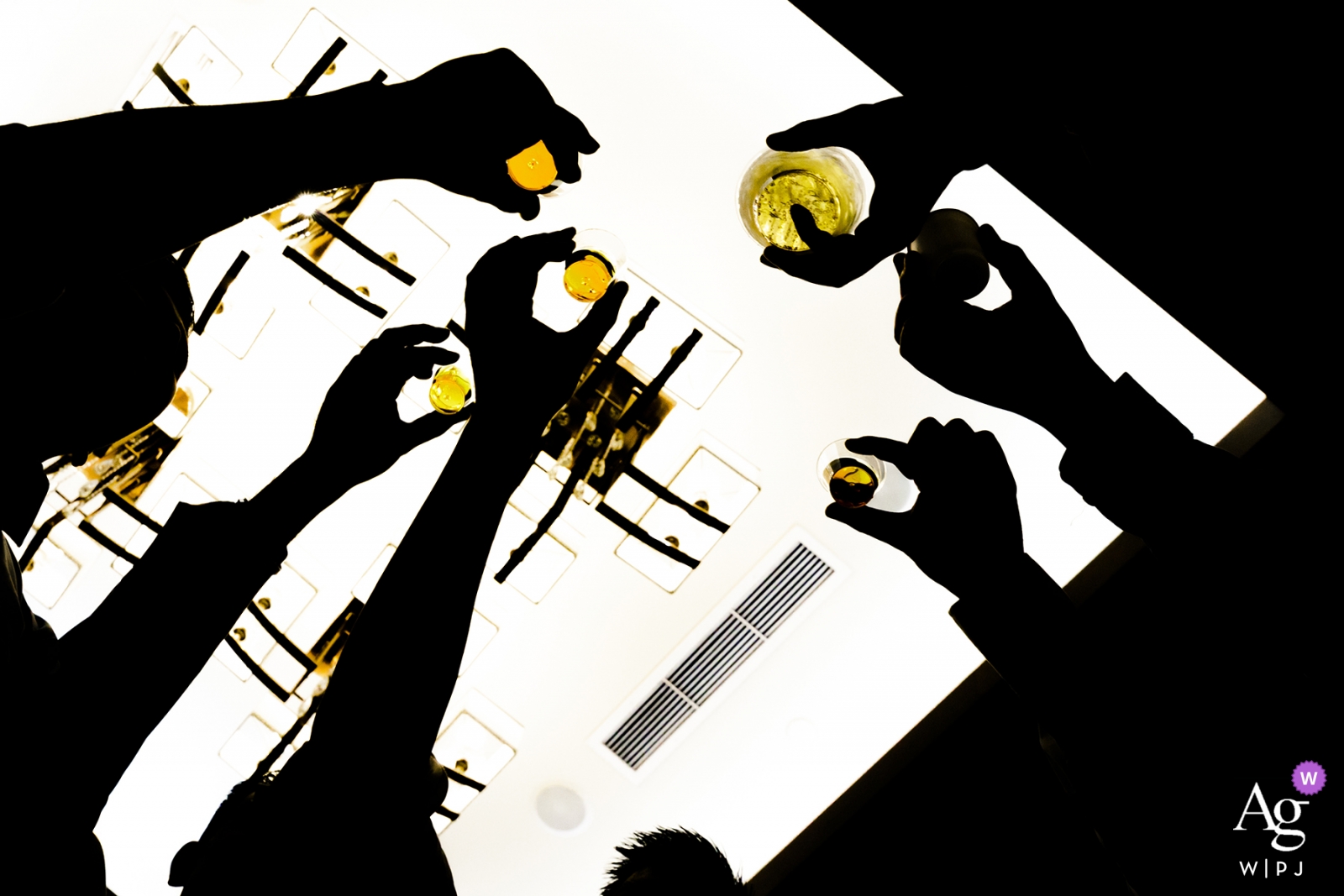 Wedding detail of silhouetted hands reaching over a table to toast in Fremont, CA
