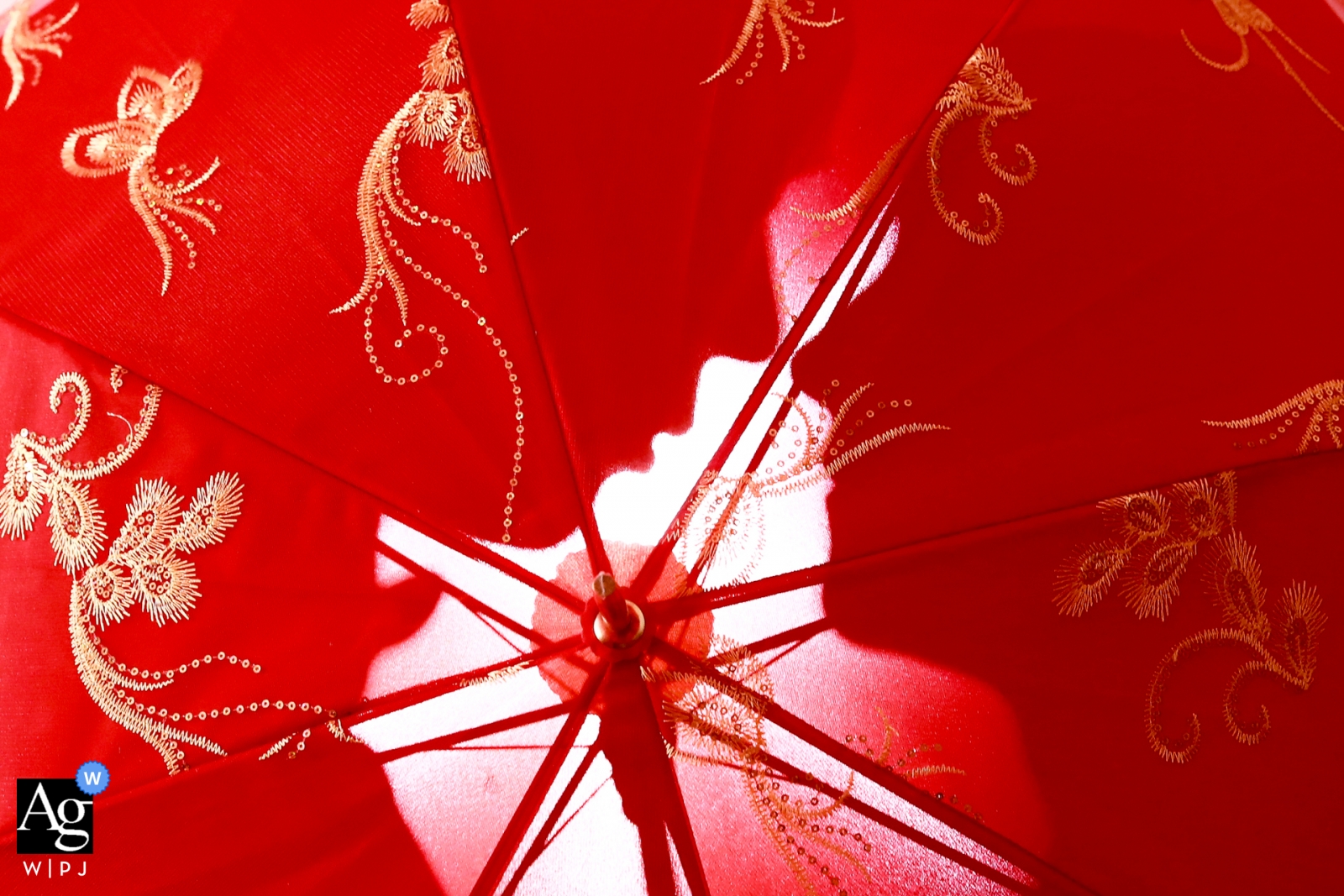 red embroidered umbrella with the silhouette of the bride and groom behind China wedding detail of a red embroidered umbrella with the silhouette of the bride and groom behind