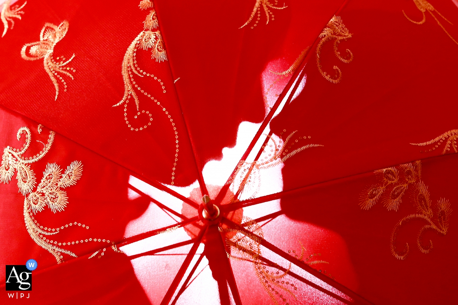 Détail de mariage Chine d'un parapluie brodé rouge avec la silhouette de la mariée et le marié derrière