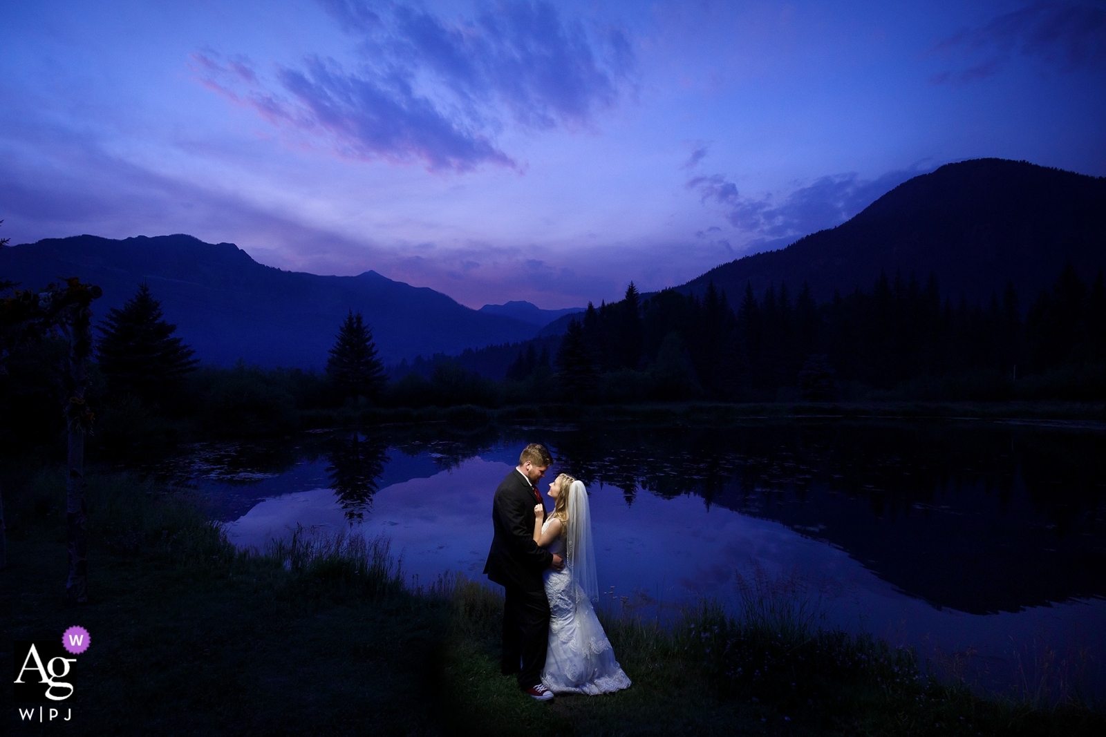 Wedding couple pose together near a pond during twilight as wildfire smoke fills the area at Bruce Spruce Ranch