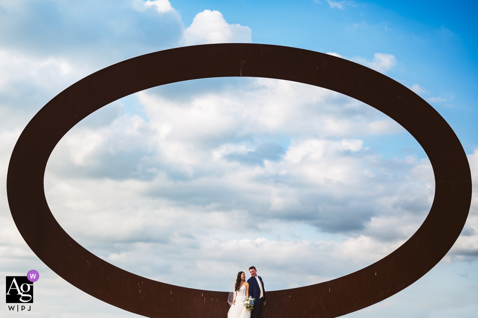 Fotos de la boda en la Toscana en el camino desde la ceremonia hasta el lugar | Pareja de pie delante del ring con nubes