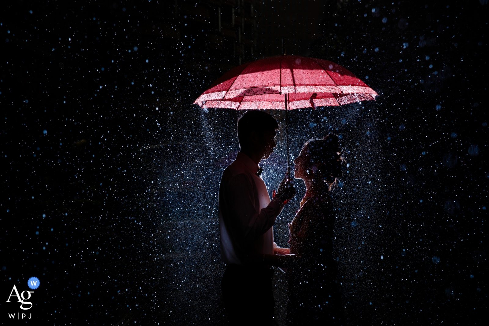 Foto von: <a href="https://www.wpja.com/photos/artistic-wedding-photographers/2559822"> Joy Qin - Longyan Hochzeitstag-Porträt Fujians, China im Regen mit rotem Regenschirm nachts
