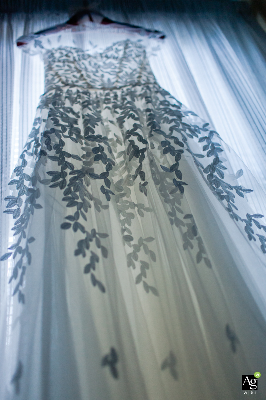 Detailfoto der Hochzeit in New York City aus dem Elternhaus der Braut – Das Kleid der Braut hängt im Fensterlicht