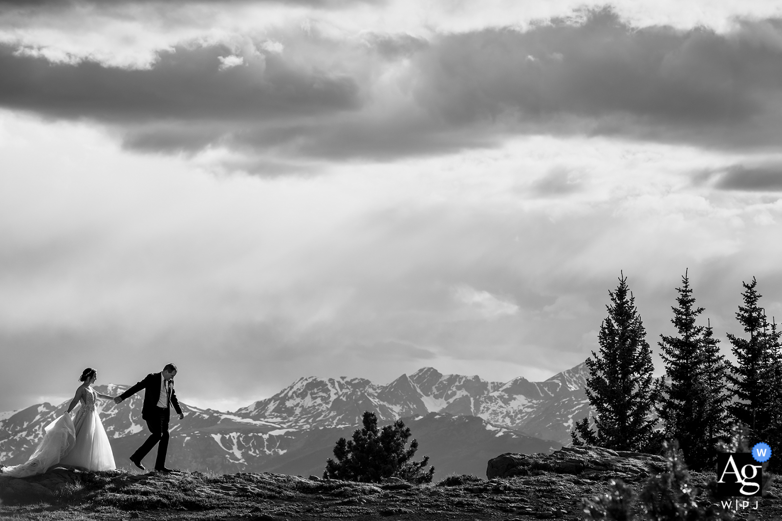 Schwarz-Weiß-Foto von Braut und Bräutigam beim Wandern in den Bergen in Camp Hale, Red Cliff, CO