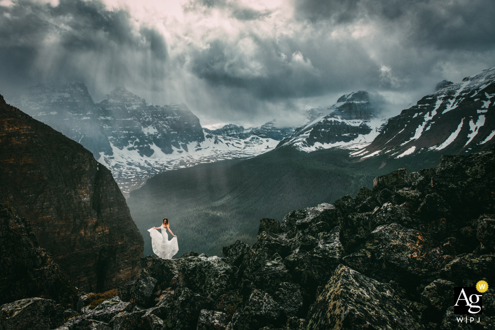 Moraine Lake, AB, Canada Bride holding her wedding dress in the mountains