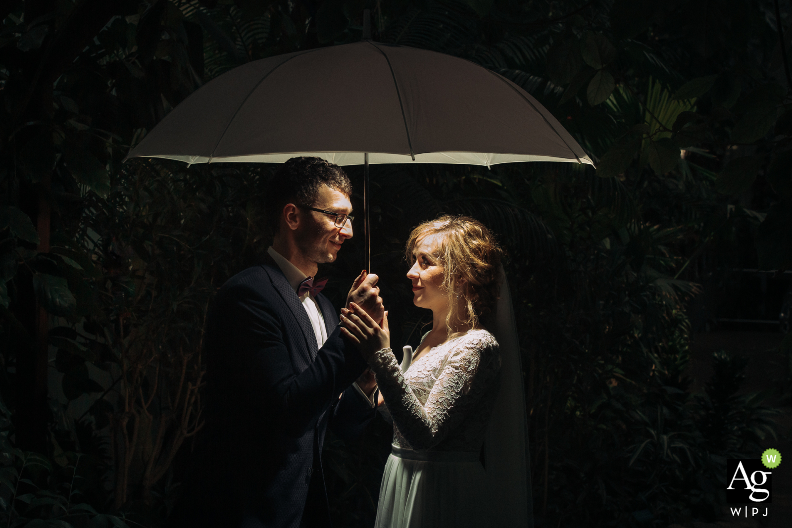 Church of Saint Albert Chmielowski in Lodz, Poland artistic wedding couple portrait of The bride and groom standing under an umbrella during a quick session after leaving the church