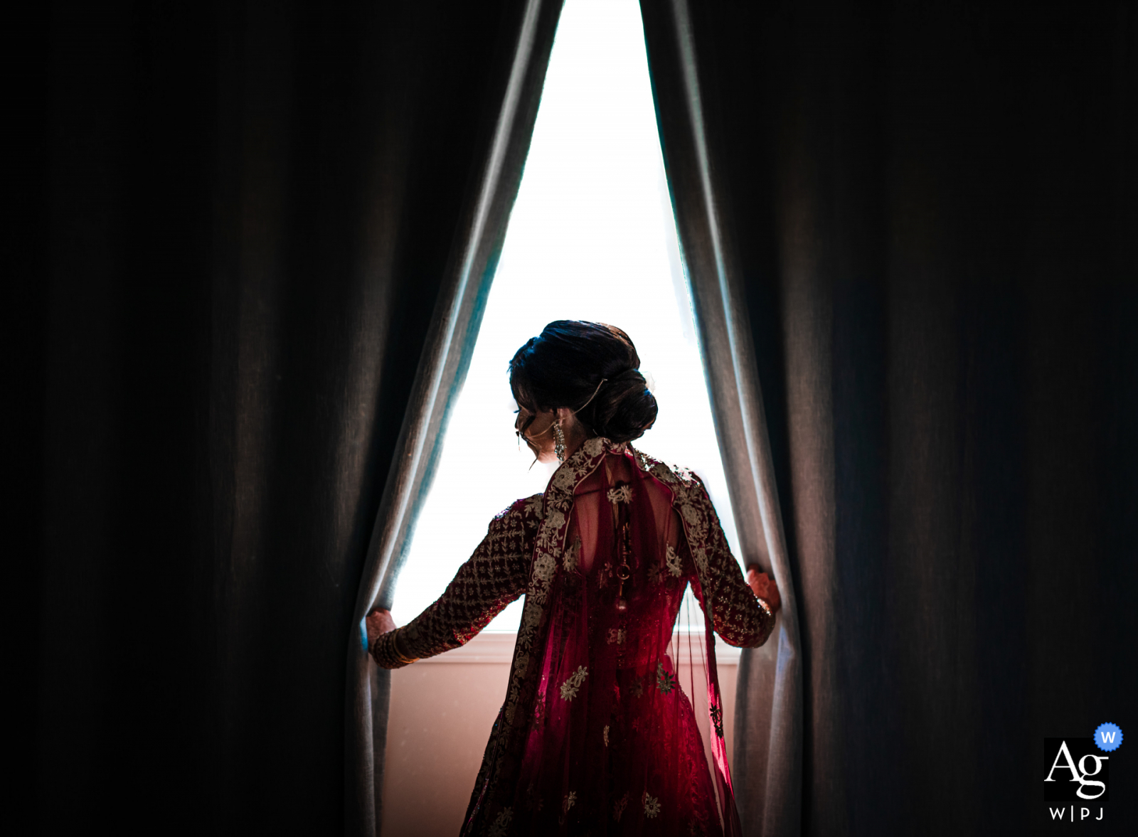 Der Hochzeitsfotograf aus Ontario hat dieses Porträt der Braut aufgenommen, die in einem Fenster zwischen den Vorhängen steht