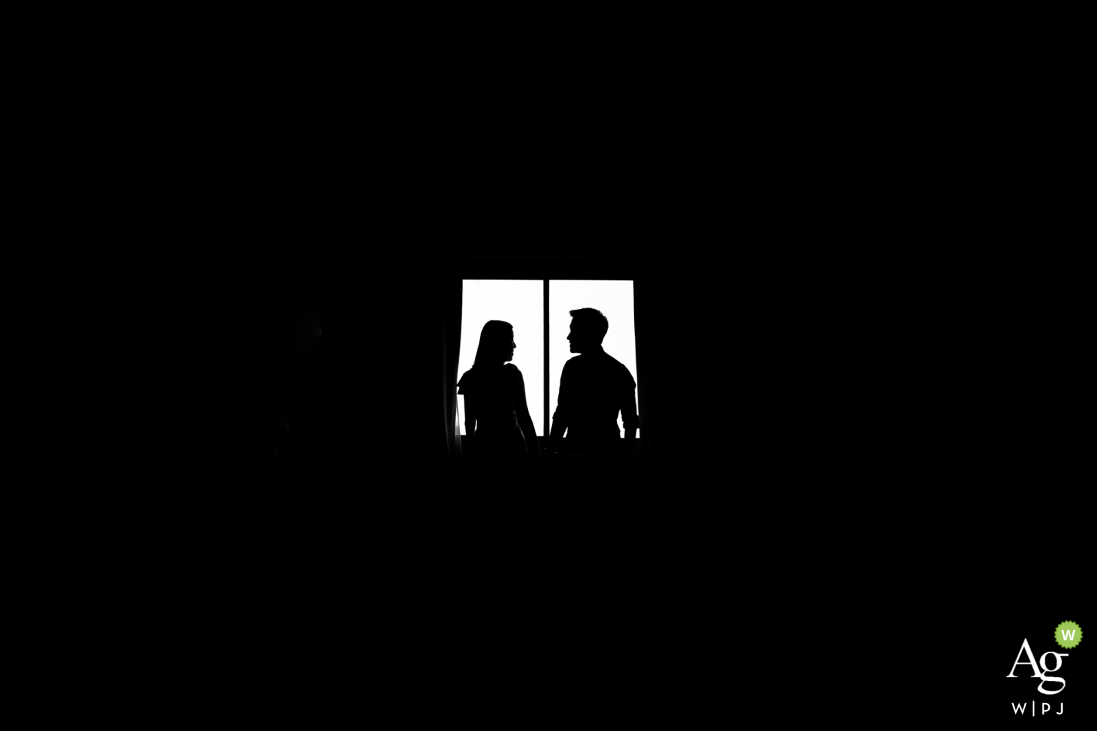 Samutprakarn black and white wedding portrait in a dark room against a window with a strong silhouette