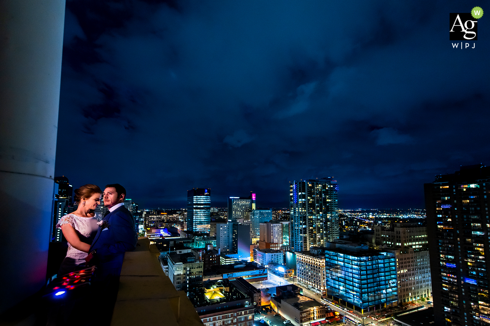 Daniels und Fisher Tower, Denver, CO künstlerisches Hochzeitspaarporträt der Braut und des Bräutigams vor der Skyline von Denver bei Nacht