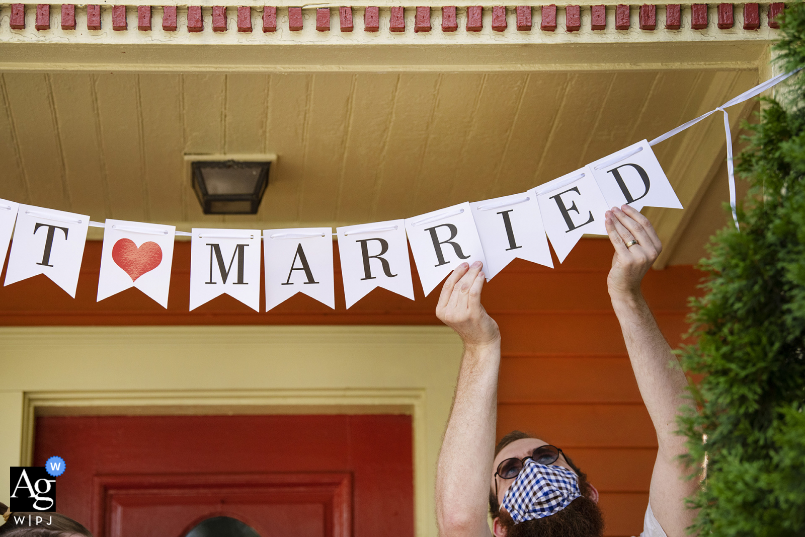 Image de mariage à domicile de Cambridge, Massachusetts, de l'officier / frère de la mariée qui raccroche le signe "Just Married" après la cérémonie