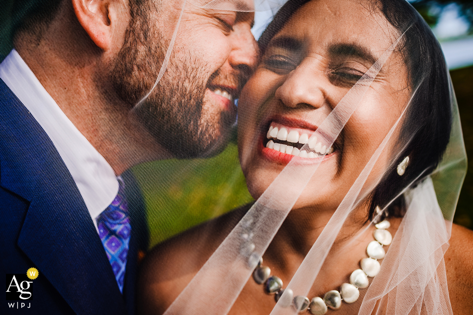 A couple laughs together under a veil while taking wedding portraits at Lincoln Park in Chicago, Illinois