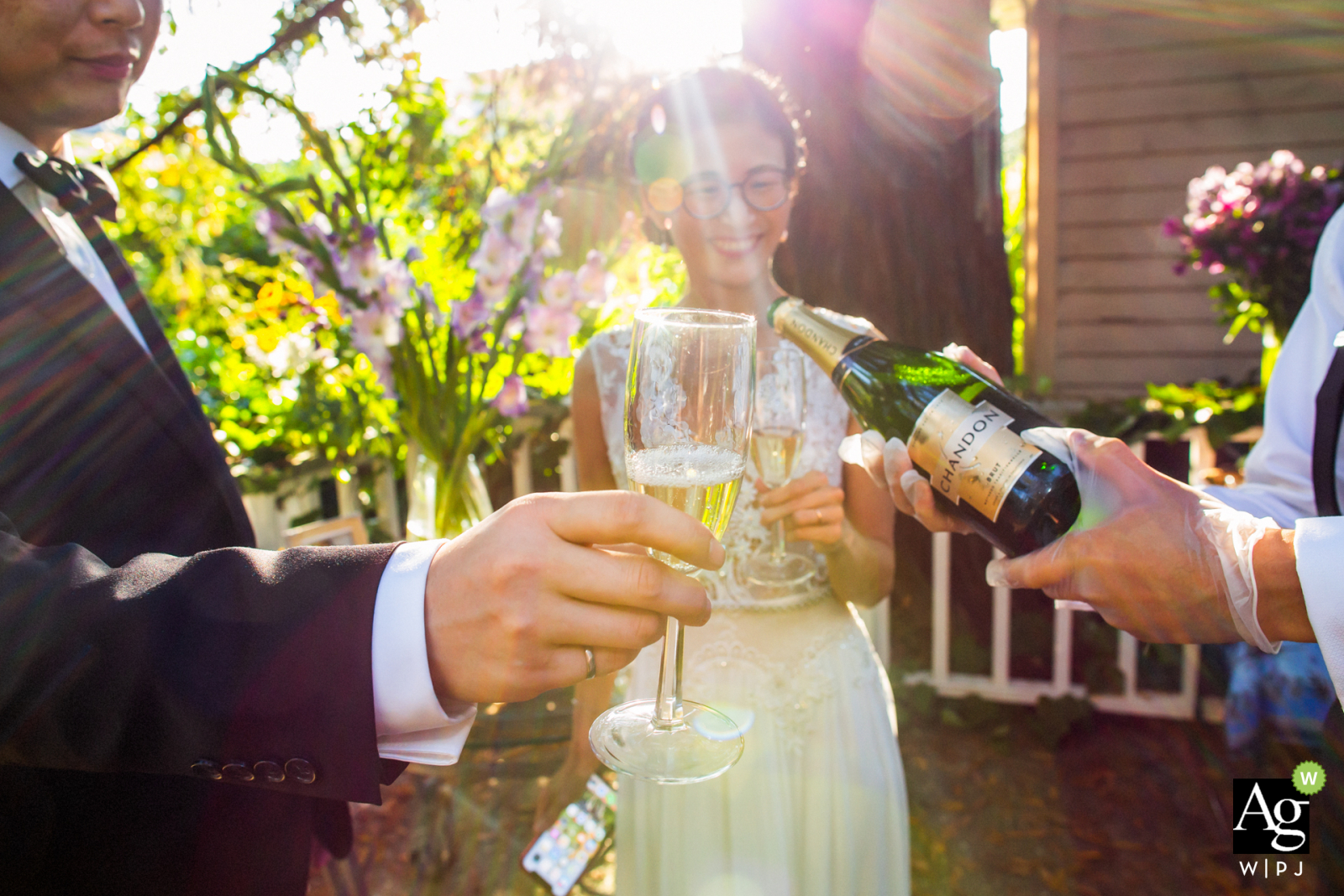 Kunsthochzeits-Detailfoto aus Oakland, Bild einer Flasche, die draußen in der Sonne eingeschenkt wird, bevor ein Prost angestoßen wird