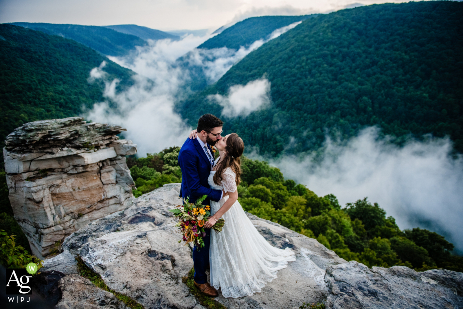 Ein Paar aus Washington DC, Vereinigte Staaten, posiert für ein Hochzeitsporträt, nachdem es auf den Felsen über den Wolken und dem darunter liegenden Tal durchgebrannt ist