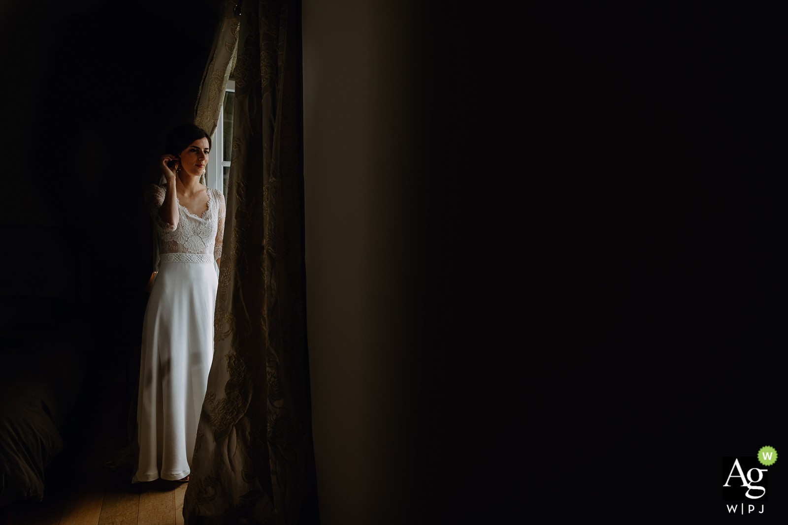 Auvergne-Rhône-Alpes wedding bride posing for a portrait next to a window opening with natural lighting