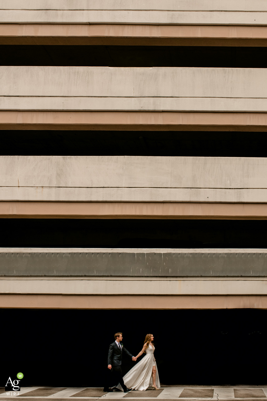 Florida wedding couple posing for a portrait in downtown Orlando showing the darkness of a parking garage across the street, for an Abbey Road type of image, positioning the couple in the walkway in direct sun with shadows