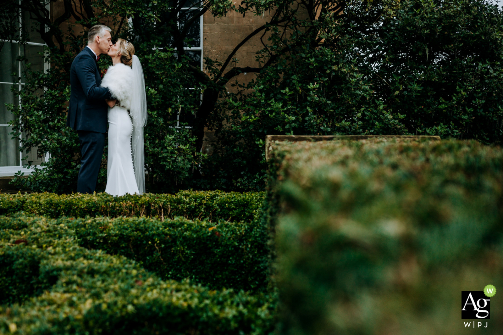 Englands Hochzeitsbraut und -bräutigam küssen sich im Garten ihres Hochzeitsortes