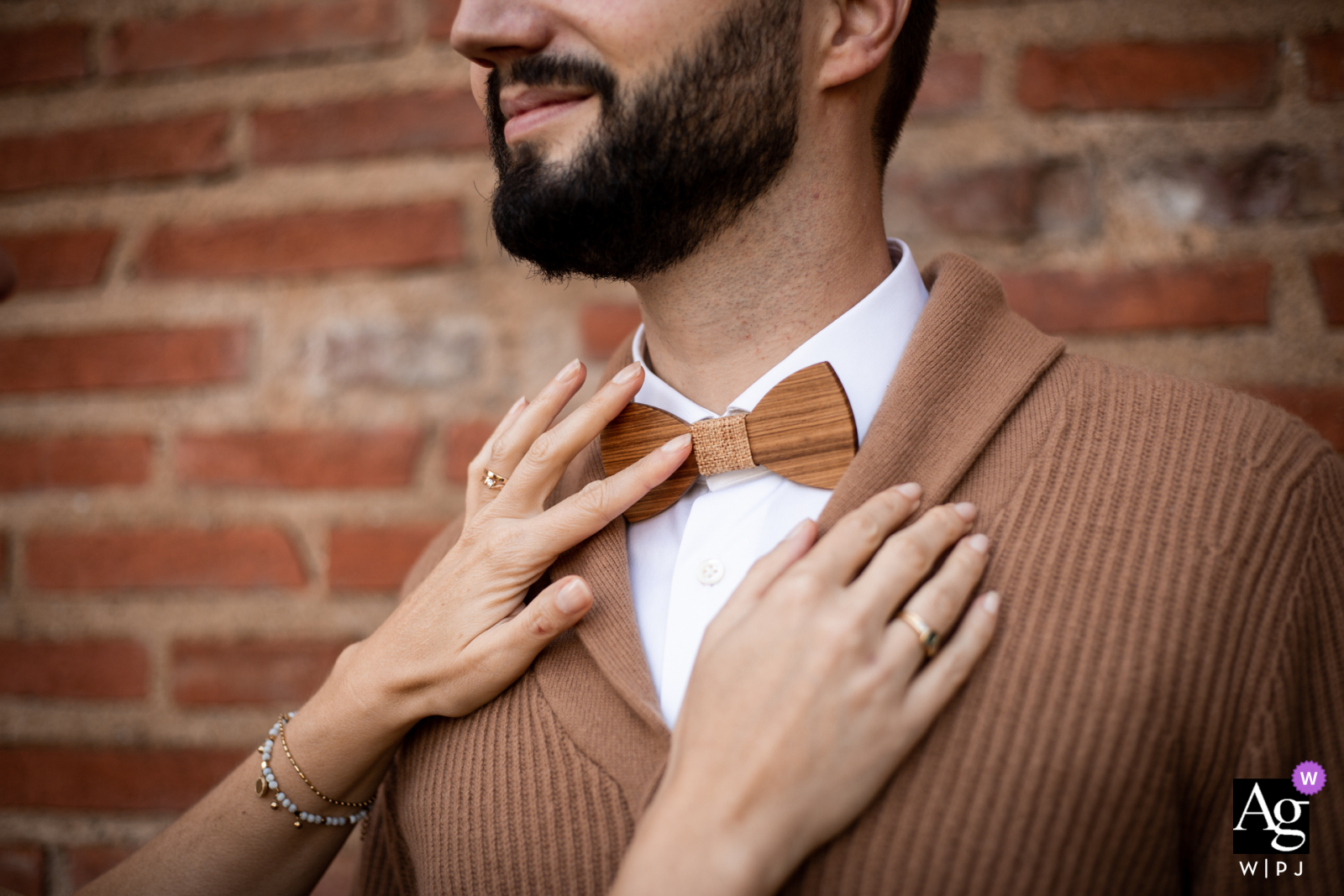 Albi street south of France creative wedding detail image of the grooms Wood bow tie against a warm brick wall and sweater