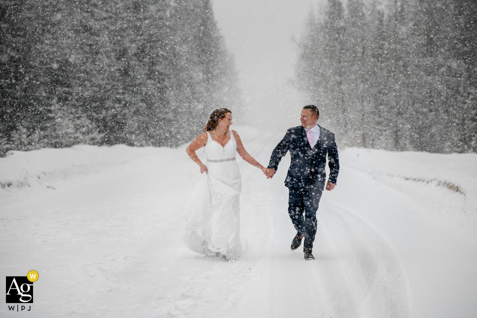 Puente natural, Field, BC, Canadá pareja creativa retrato de boda de la novia y el novio divirtiéndose durante las nevadas