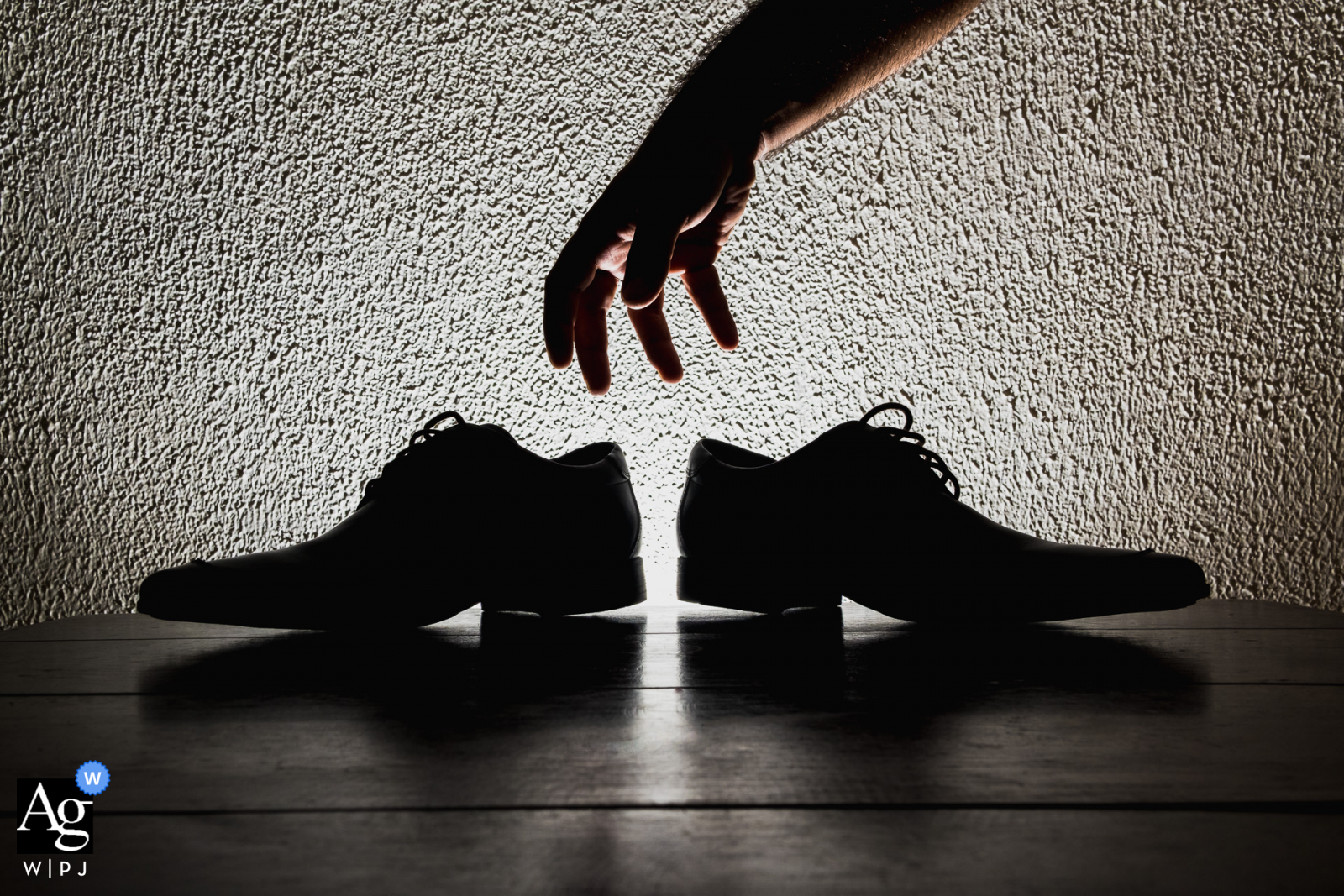 Artistic wedding photography from Hotel Quilombo, União dos Palmares-AL showing a silhouette of the groom's hand picking up his shoes