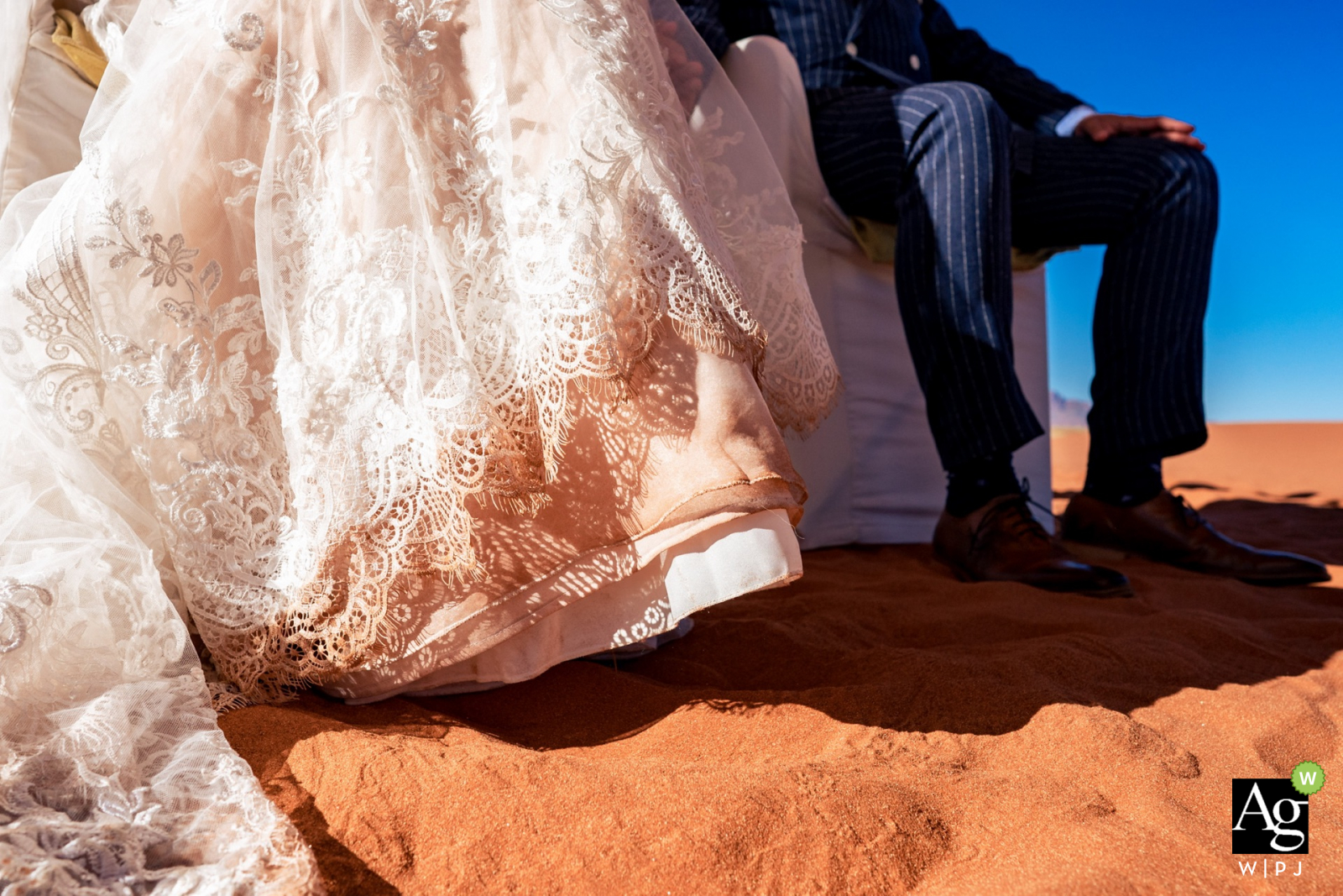 Künstlerisches Namib-Rand-Reserve-Hochzeitsdetailbild in der Wolwedans Dunes Lodge in Afrika mit Wüstensand, dem Brautkleid und den Schuhen des Bräutigams